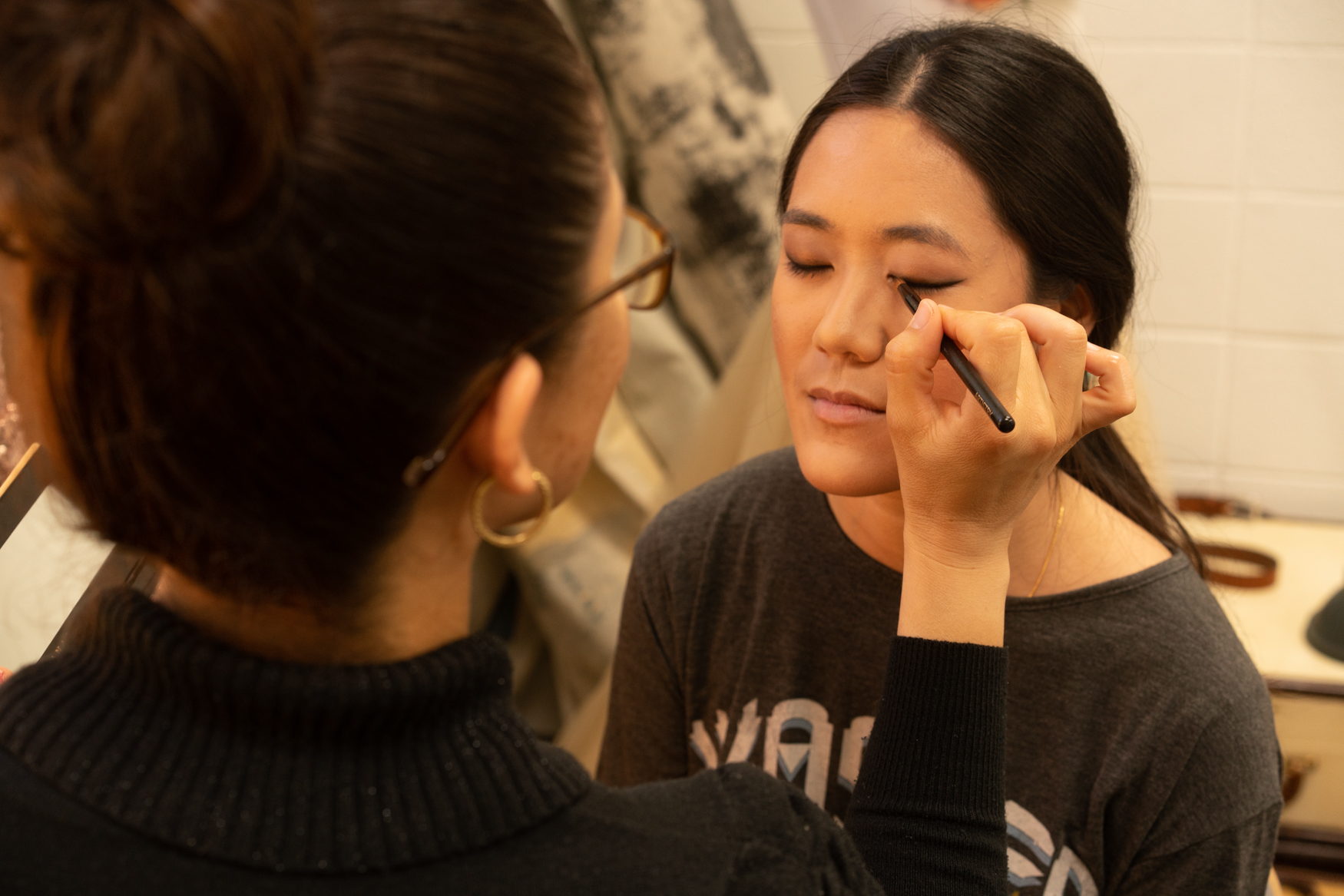 Photo of Veronica applying makeup on Vi for her portrait shoot at David Suh Photography in Sacramento